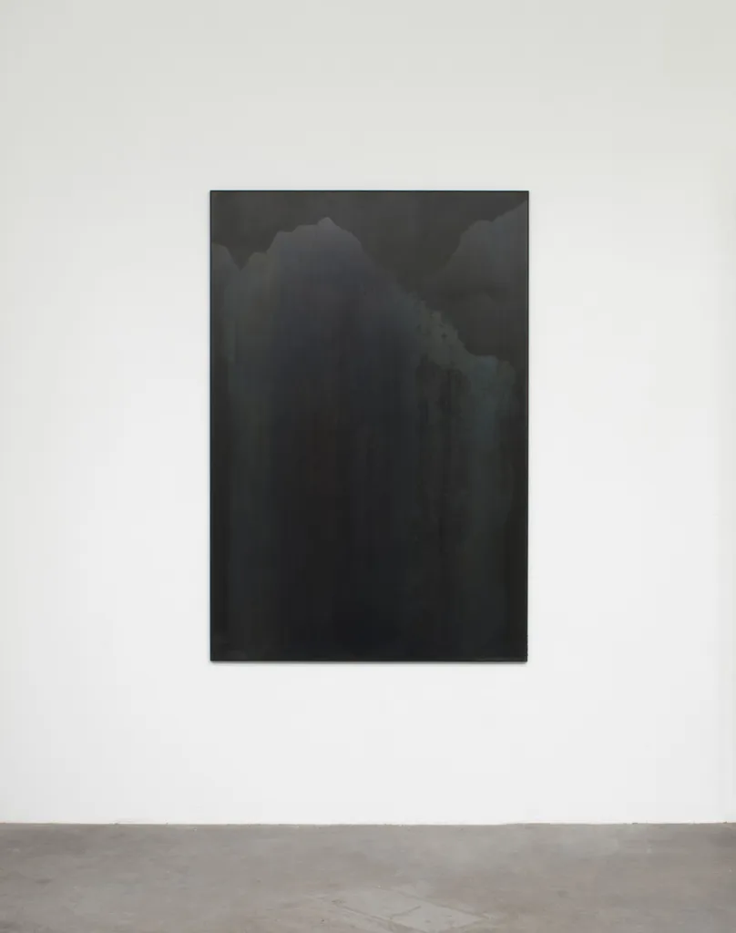 A small panel black steel plate piece that represents a mountain range and sky