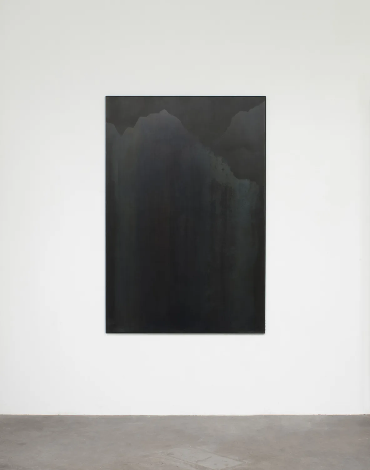 A small panel black steel plate piece that represents a mountain range and sky
