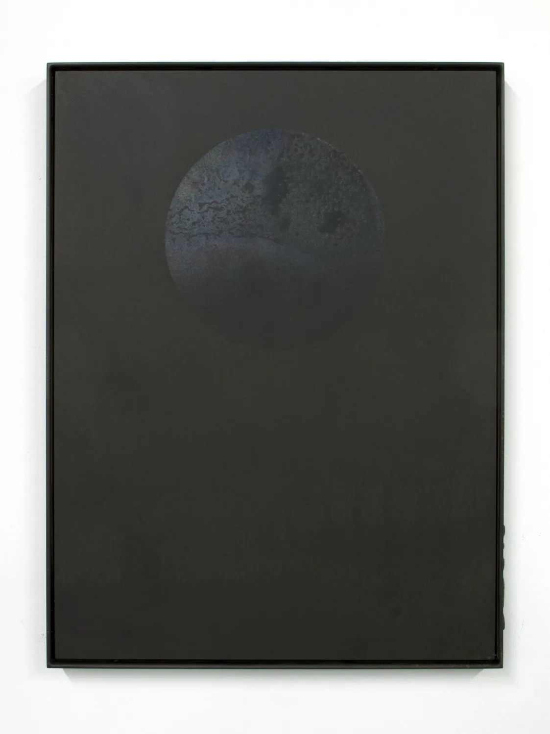 A small panel black steel plate piece that represents a perfect floating circle becomes reminiscent of the moon