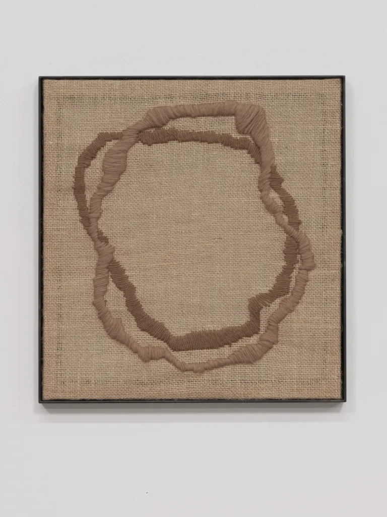 A textile artwork that shows a vessel, an egg, a portal or a celestial shape that embroidered on a burlap
