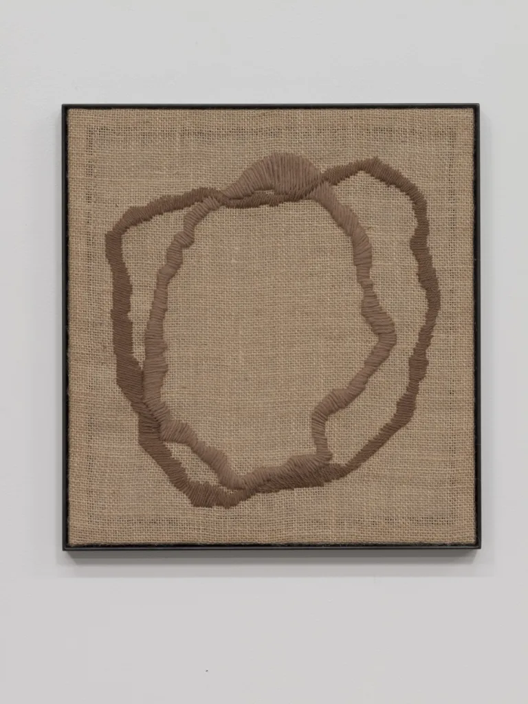A textile artwork that shows a vessel, an egg, a portal or a celestial shape that embroidered on a burlap