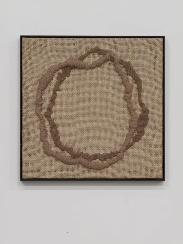 A textile artwork that shows a vessel, an egg, a portal or a celestial shape that embroidered on a burlap