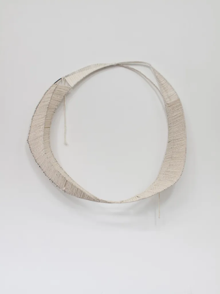 A textile artwork that shows a vessel, an egg, a portal or a celestial shape that embroidered on a burlap