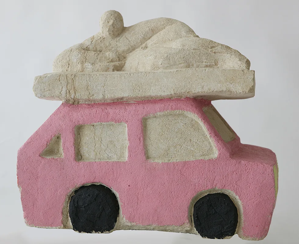 A sculpture of a car and on top of that is a human figure