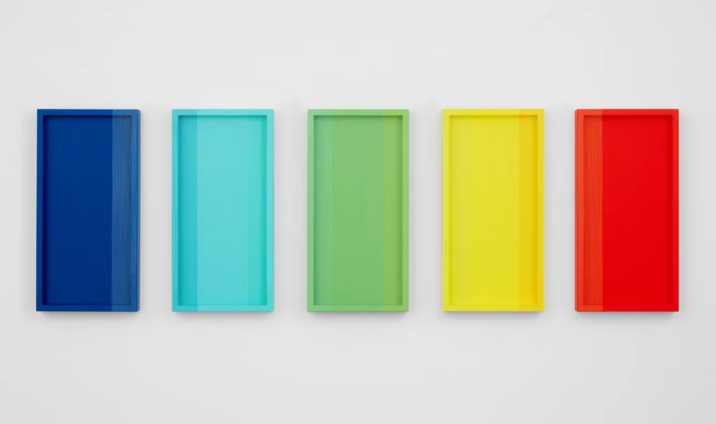 A wall installation that consists of five panels that are painted of tomato red, yellow, green sky blue and dark blue