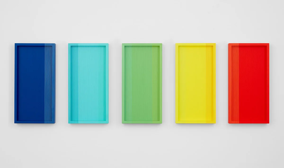 A wall installation that consists of five panels that are painted of tomato red, yellow, green sky blue and dark blue