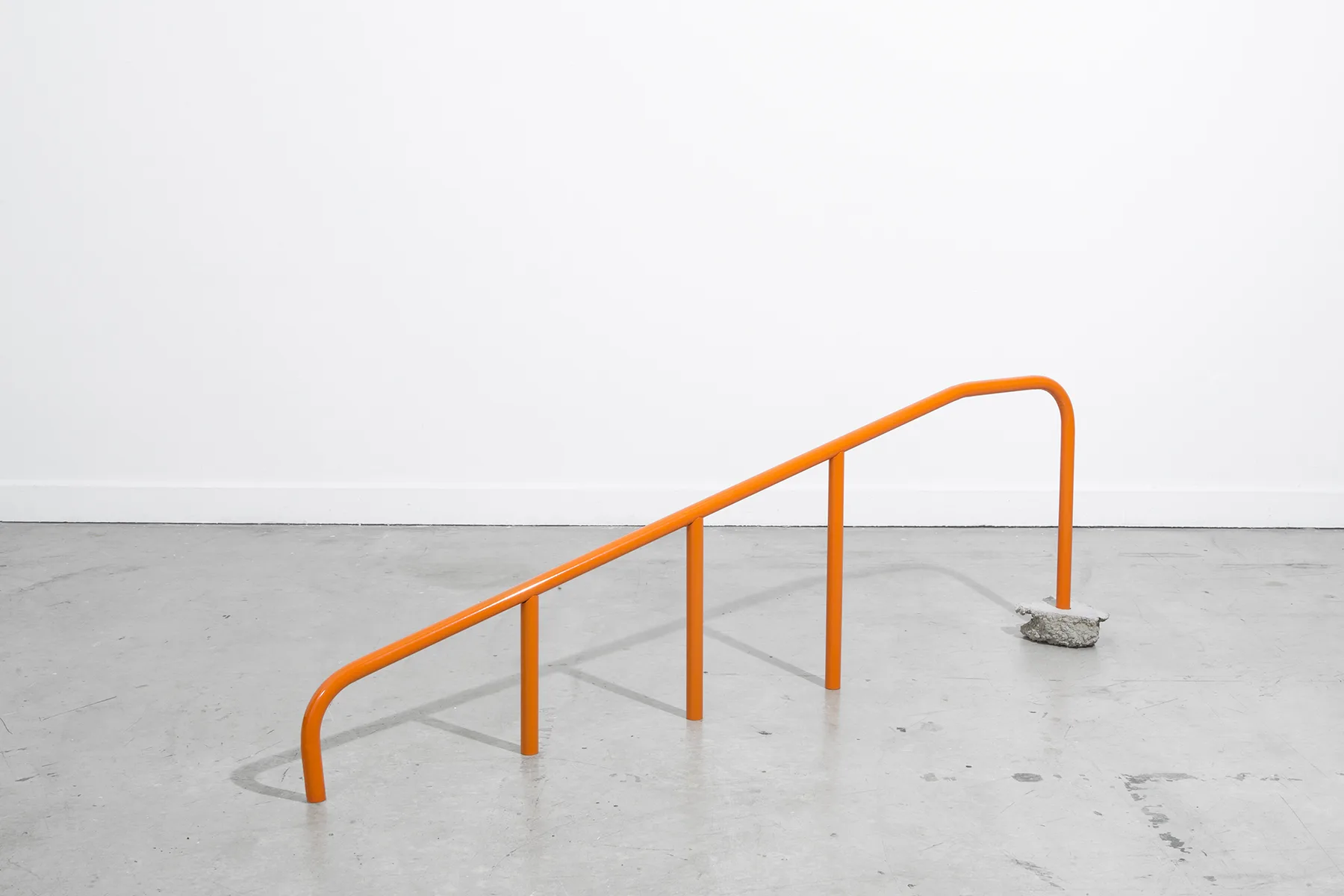 A sculpture on the floor that is made of coated steel and assemble as a handrail