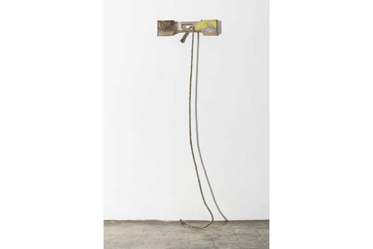 A sculpture focuses on a rope that is attached on a flat wood