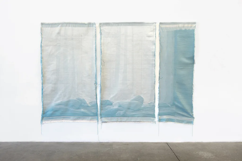 A woven tapestry depicts photographic image of two nude bodies