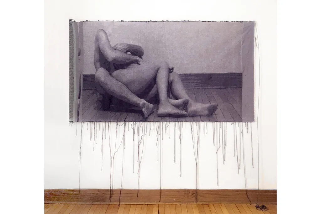 A woven tapestry depicts photographic image of two nude bodies that is intimate
