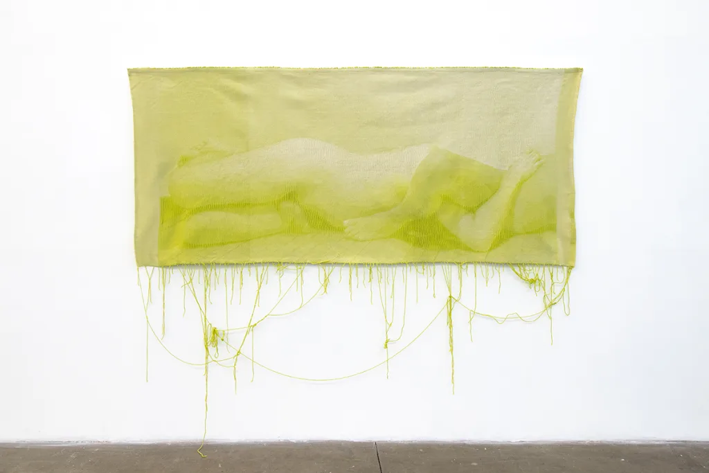 A green woven tapestry depicts photographic image of two nude bodies that is intimate