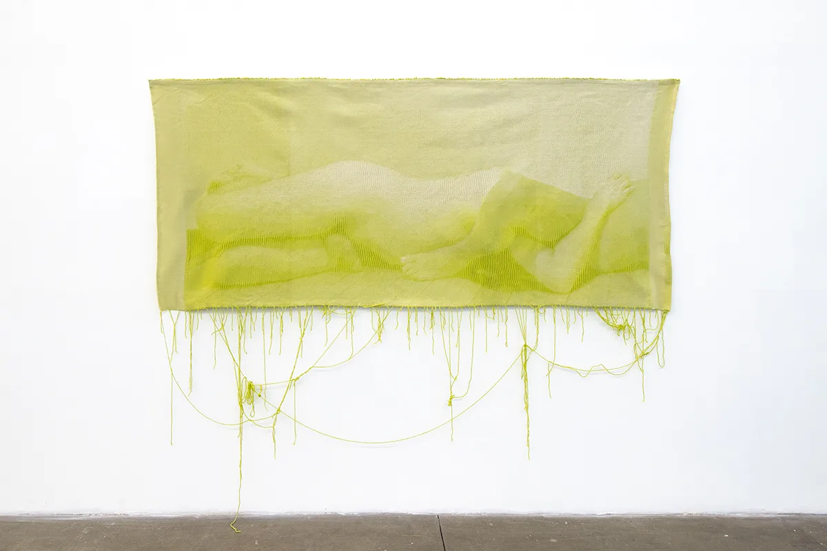 A green woven tapestry depicts photographic image of two nude bodies that is intimate
