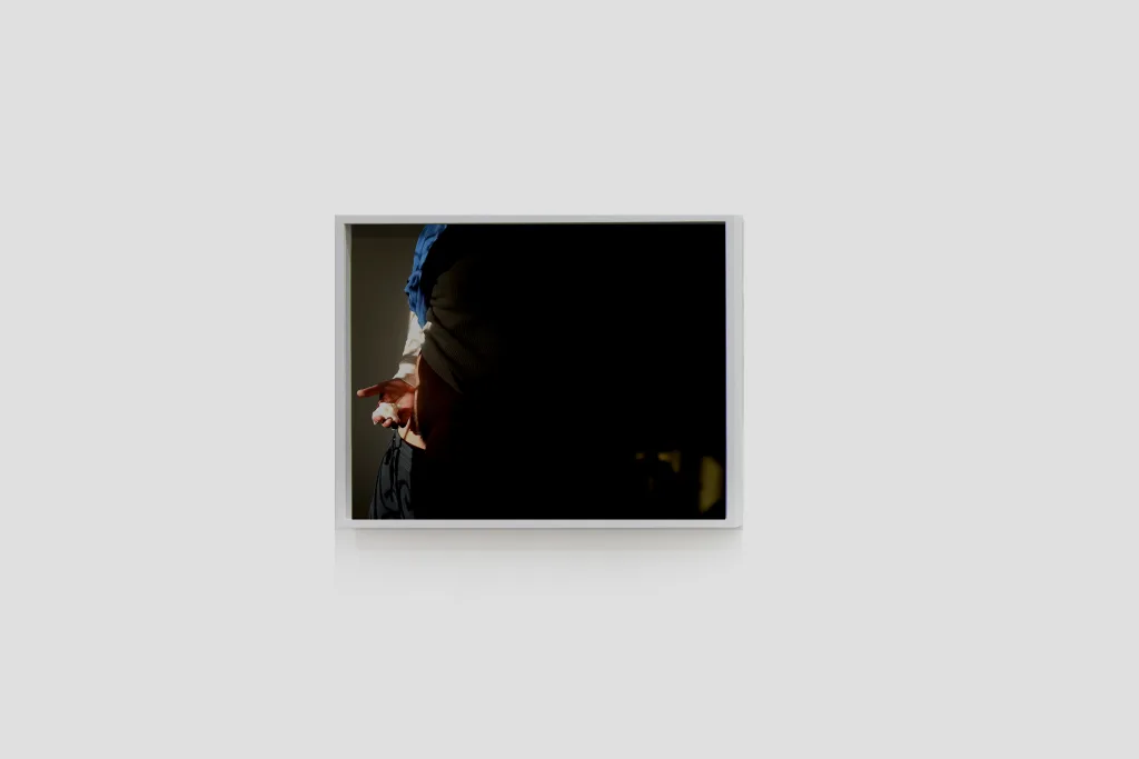 Installation image of Ohan Breiding's Playing Submarine show, of one portrait hanging on the wall. It shows a man is holding like a cottage cheese object with a right hand