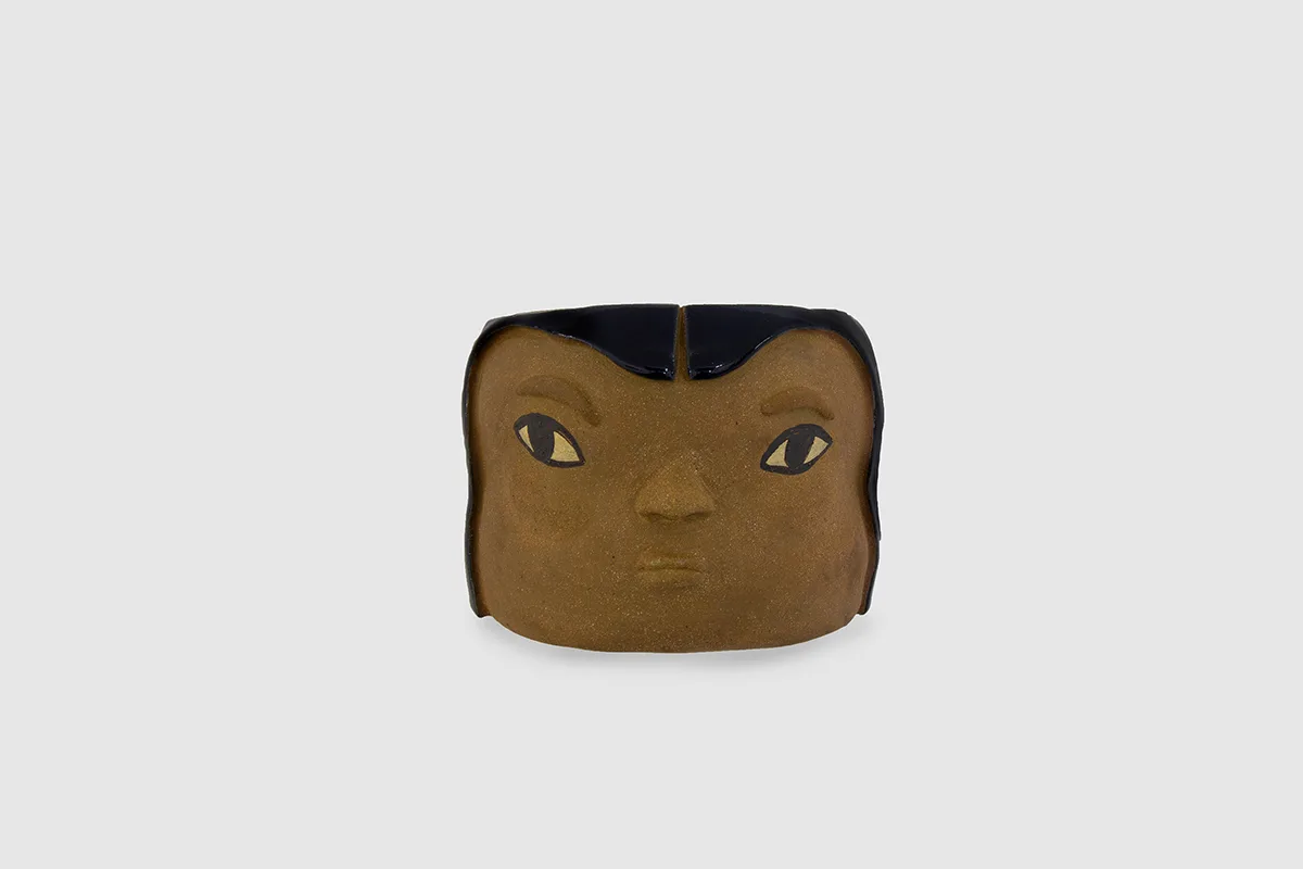 A brown ceramic human head with black hair