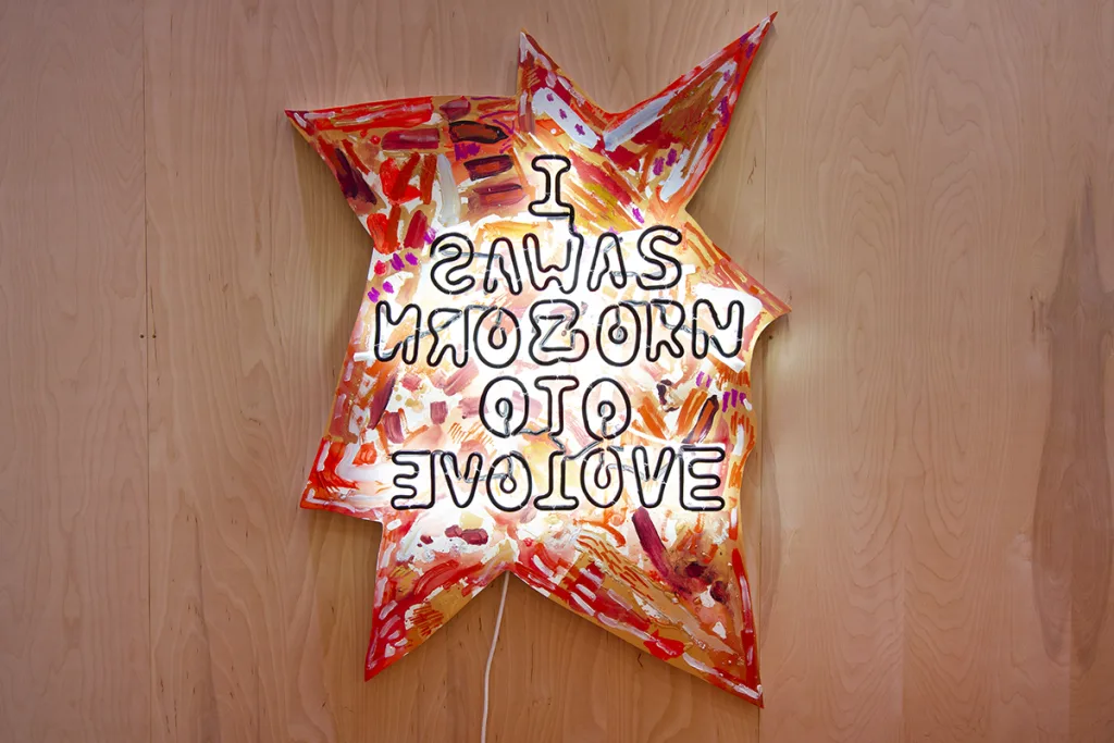 A star-like shaped painting with neon letters that spell out 'I was born to love' in a mirror format