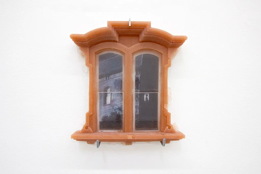 A brown window and a picture of a black house attached to a glass of the window