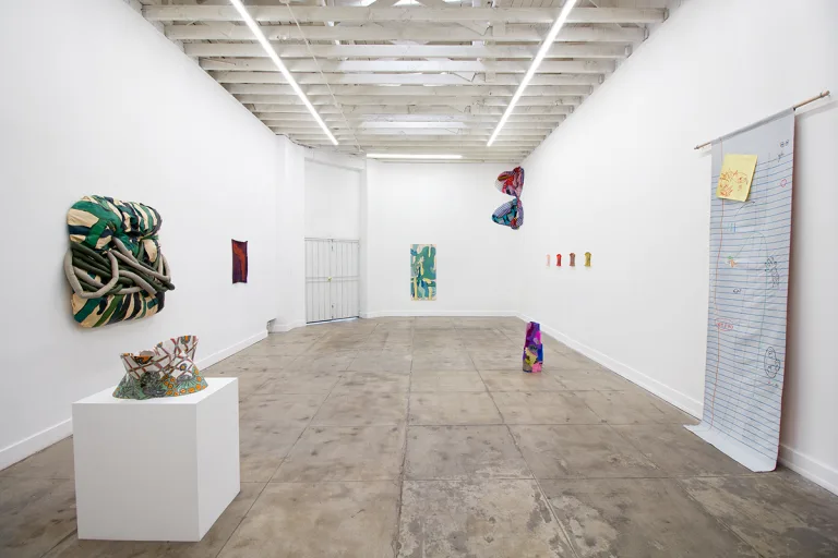 Installation image of Ring Down the Curtain that shows a wall installations, sculptures, paintings and tapestries.