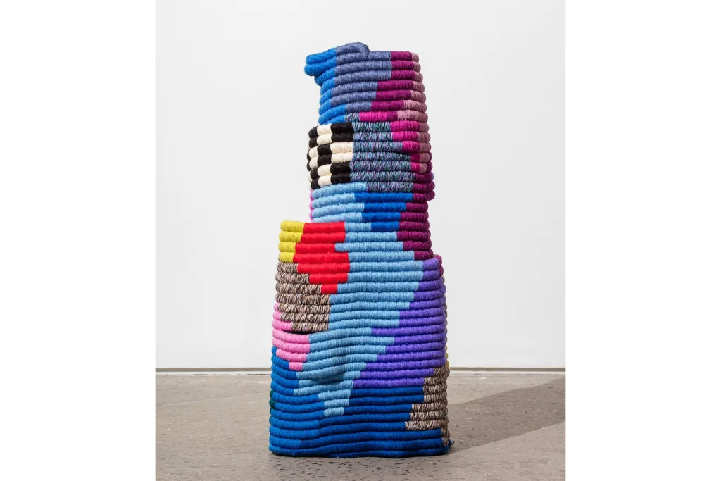 A sculpture that built of bright and dark color looms that are hand woven, rope coiled, latch hooked, and sewed