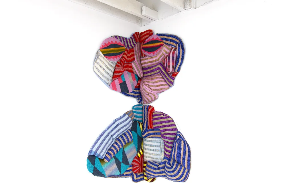 A wall installation that is made up of handwoven cloth and some fabric stuffing