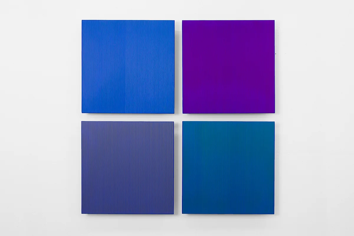 A wall installation that has a four square panels that are painted of blue, indigo and violet