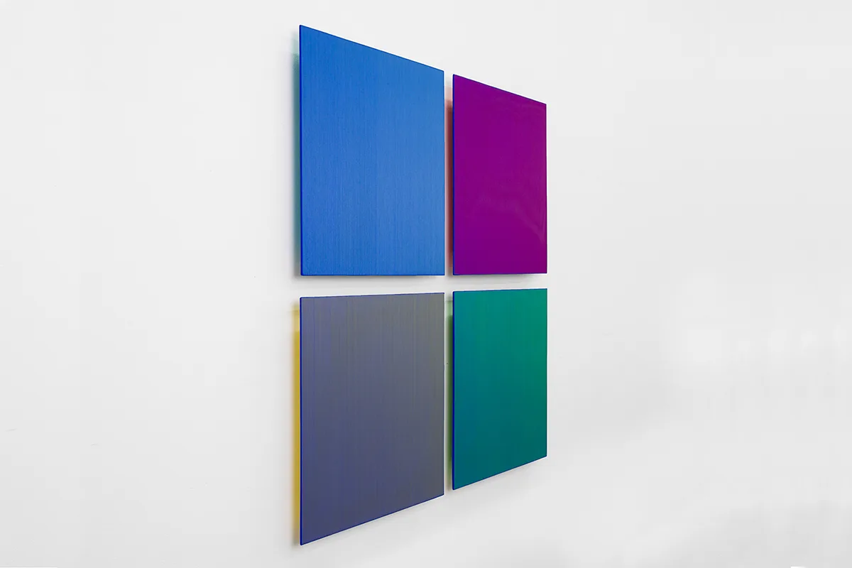 A side view image of a wall installation that has a four square panels that are painted of blue, indigo and violet
