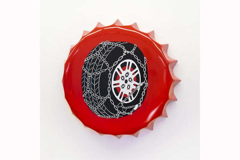 A metal cap-shaped painting features a black tire that is surrounded by white chains