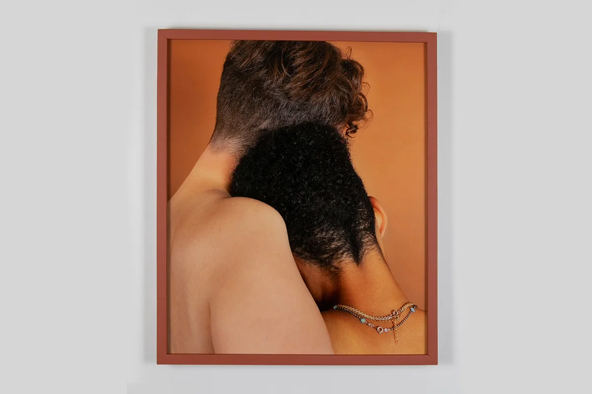 A photo of a two human figures with their back facing us. The one on the right is leaning her head on the man's right shoulder.