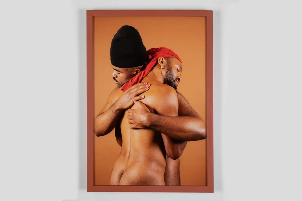 A photo of two male figures who are nuzzling, pressing or weaving their bodies together.