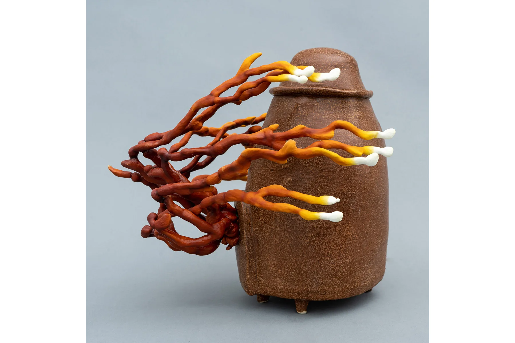 A sculpture by artist Sam Shoemaker of a stone shape with mushrooms growing off of it.