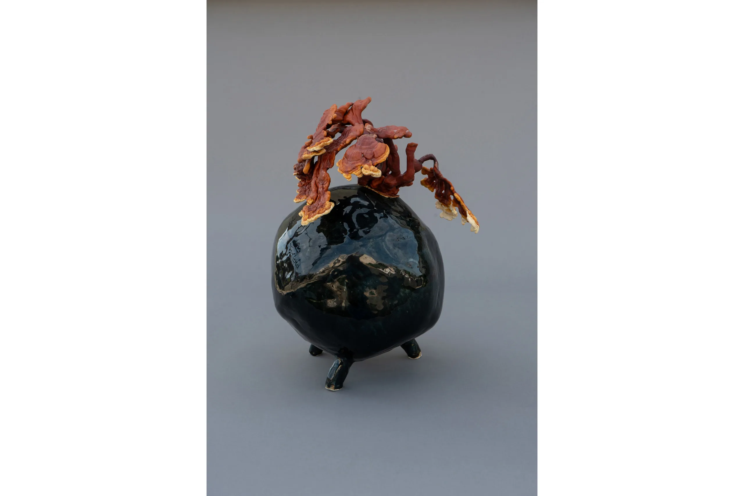 A sculpture by artist Sam Shoemaker of a stone shape with mushrooms growing off of it.