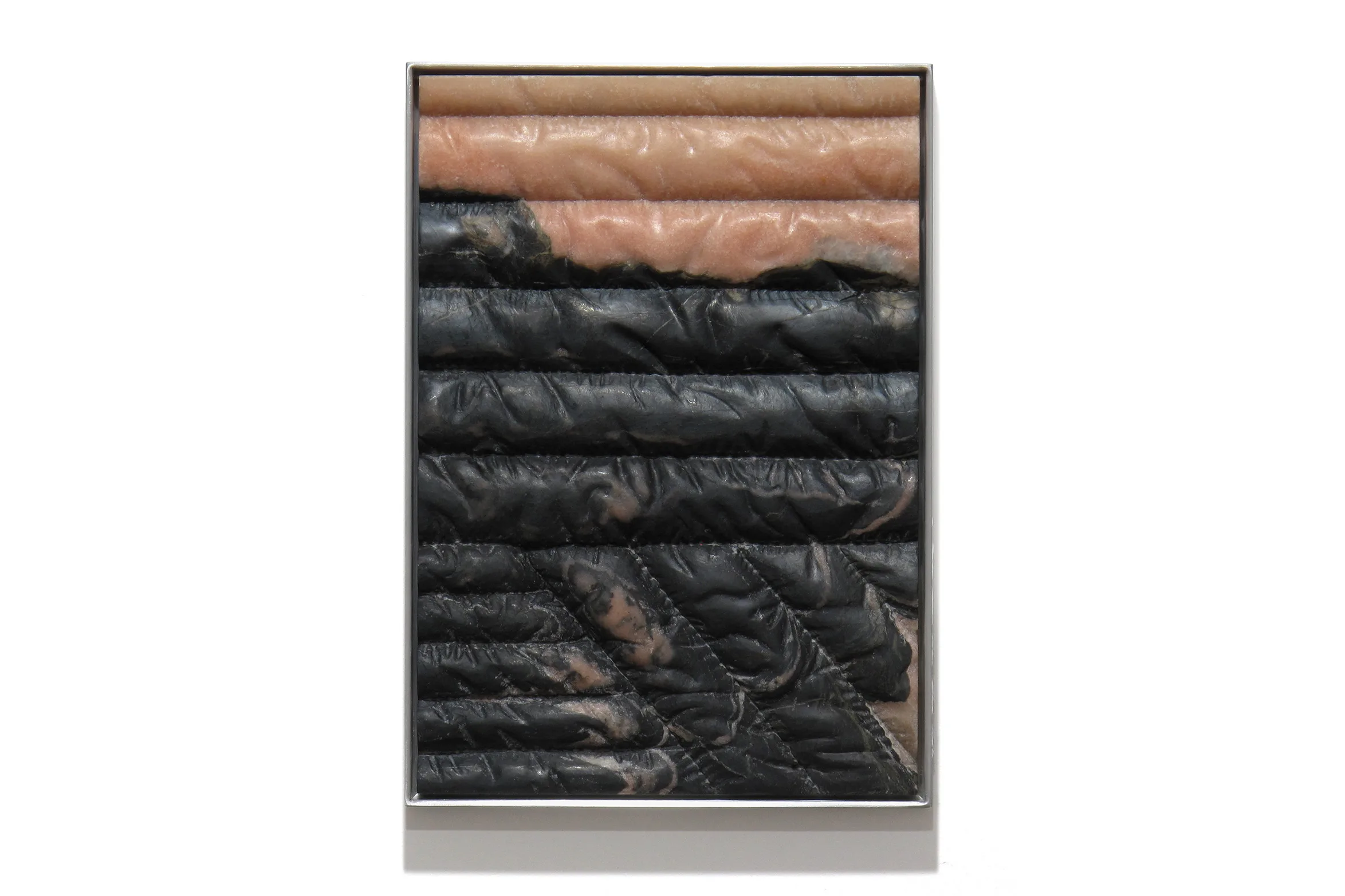 A carved marble sculpture by artist Devin Farrand depicting a puff jacket (pink and black marble).