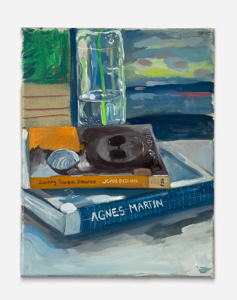 two books in front of a clear vase with a flower vine inside