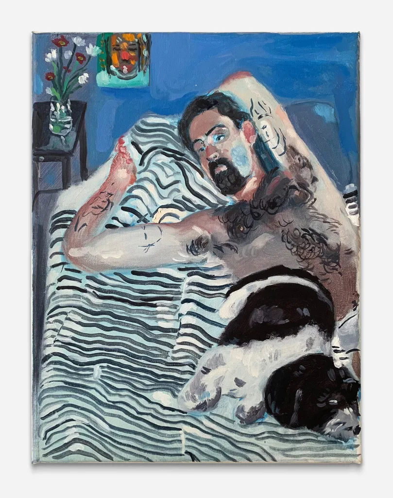 a man lays with his eyes open in bed next to a sleeping black and white dog. The blankets are striped black and white. There is a vase in the background with flowers and a painting on the wall next to them.