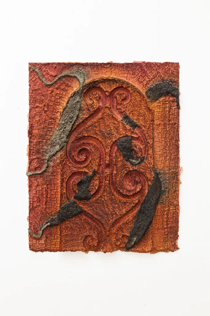 Reddish orange handmade dyed paper with a metal fencing pattern embossed at the center
