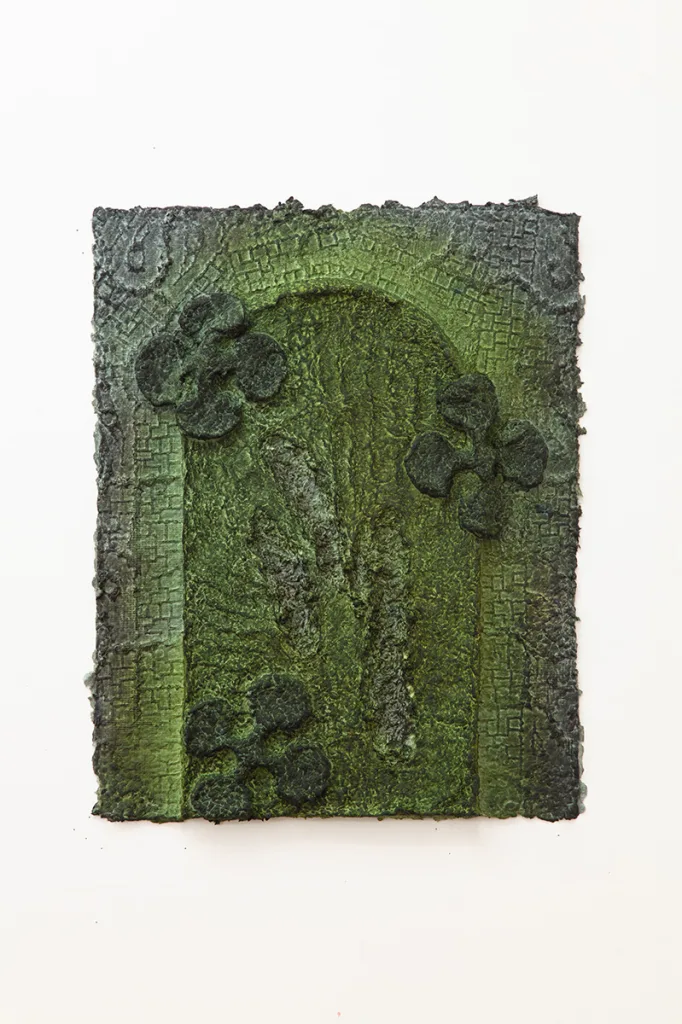 Green handmade dyed paper with a floral pattern, archway, and underlying grid pattern.