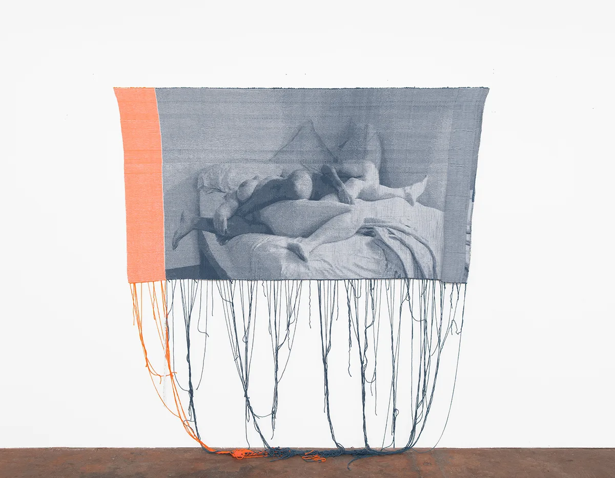 A blue and orange woven tapestry depicting two figures on a bed