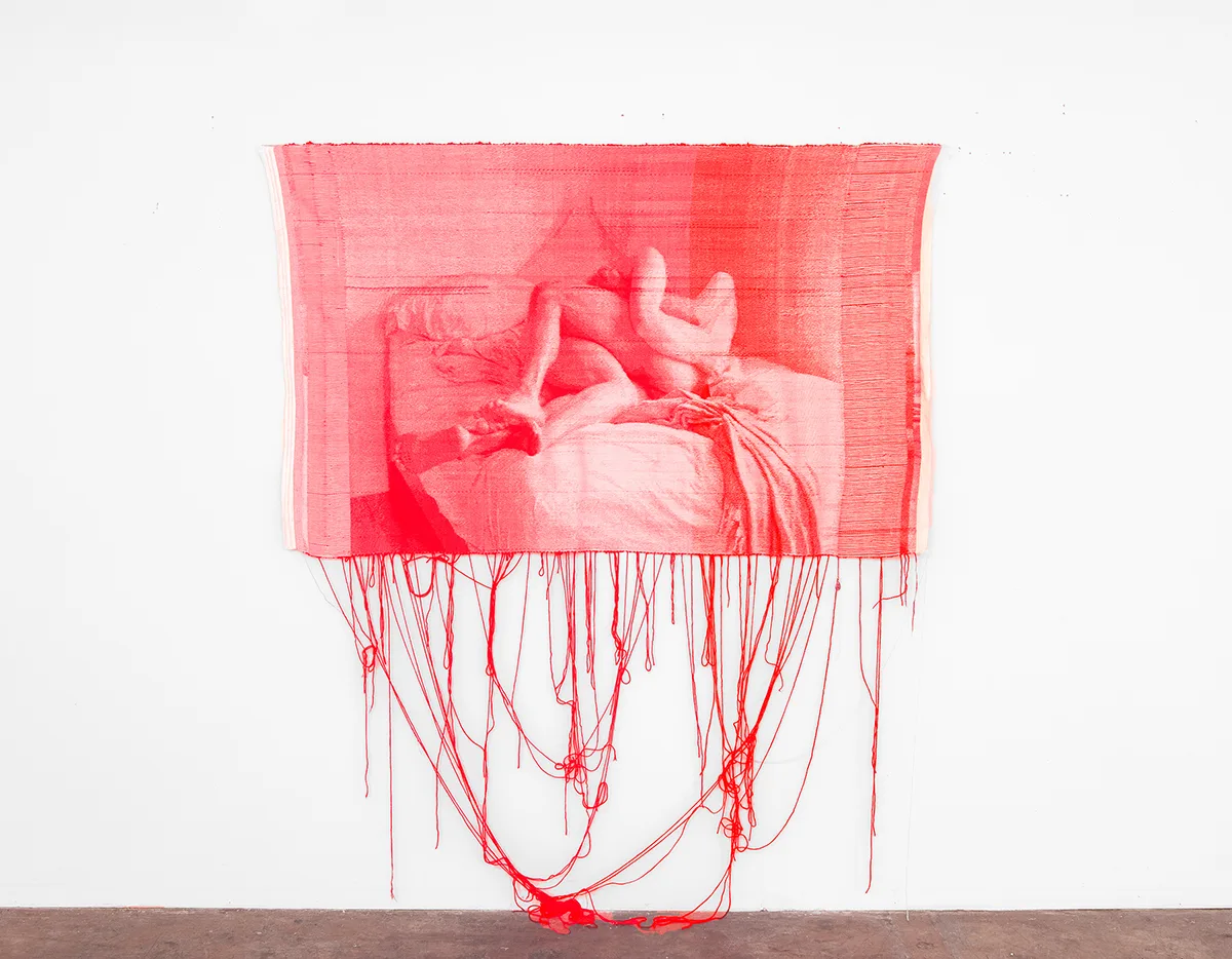 A fluorescent pink woven tapestry depicting two figures on a bed