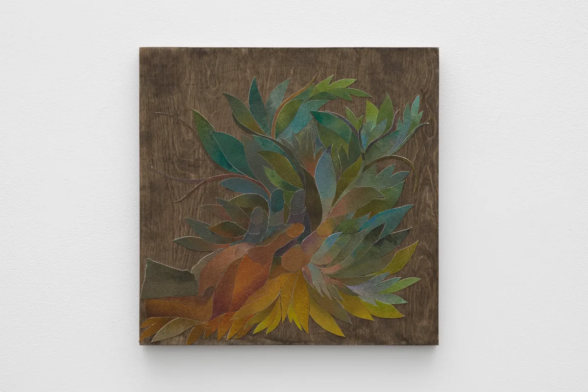 Ink on cut paper arranged to form an opened hand, facing upwards within a bunch of leaves and branches. Mounted on a wood panel with a dark gray stain
