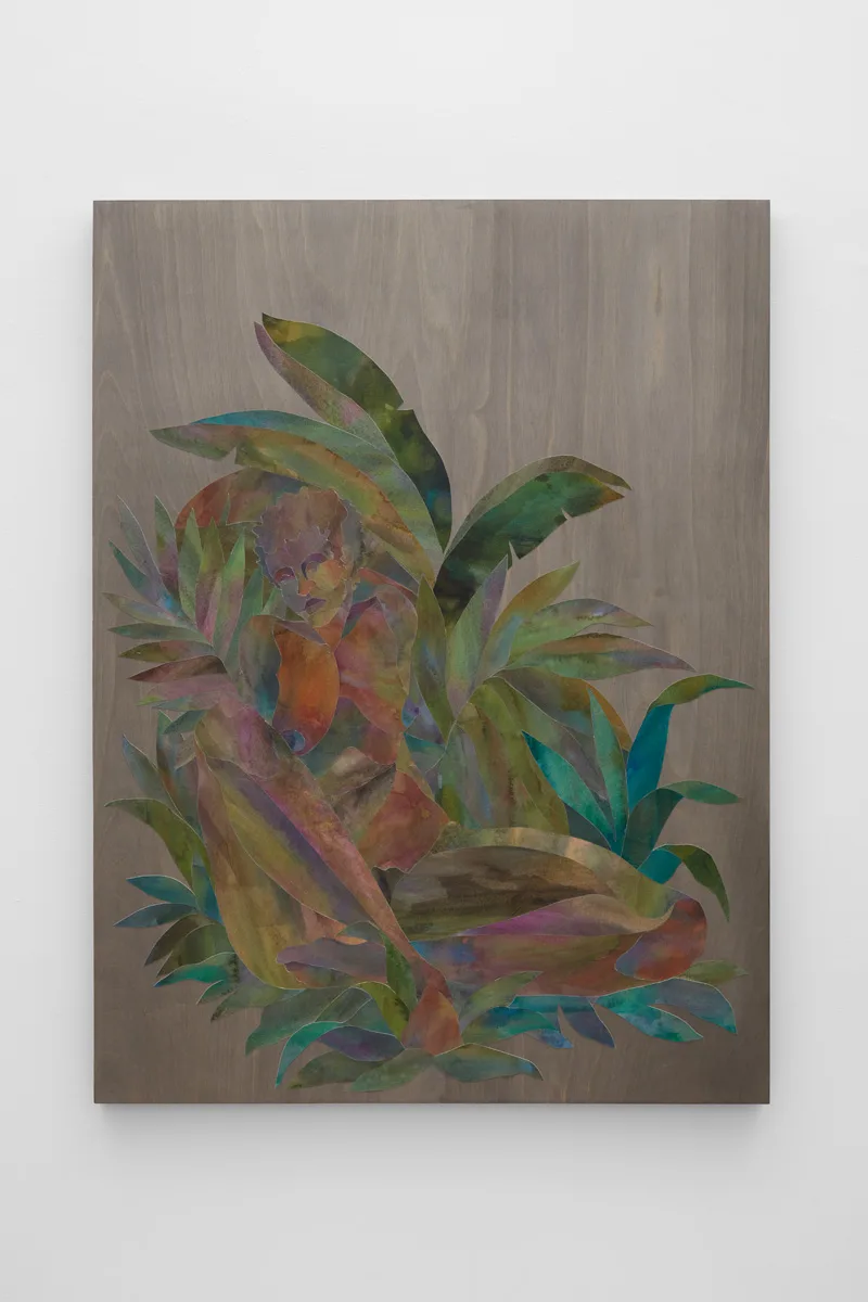 Ink on cut paper arranged to form a figure sitting upright with their legs crossed in a bed of foliage. Mounted on a wood panel with a dark gray stain