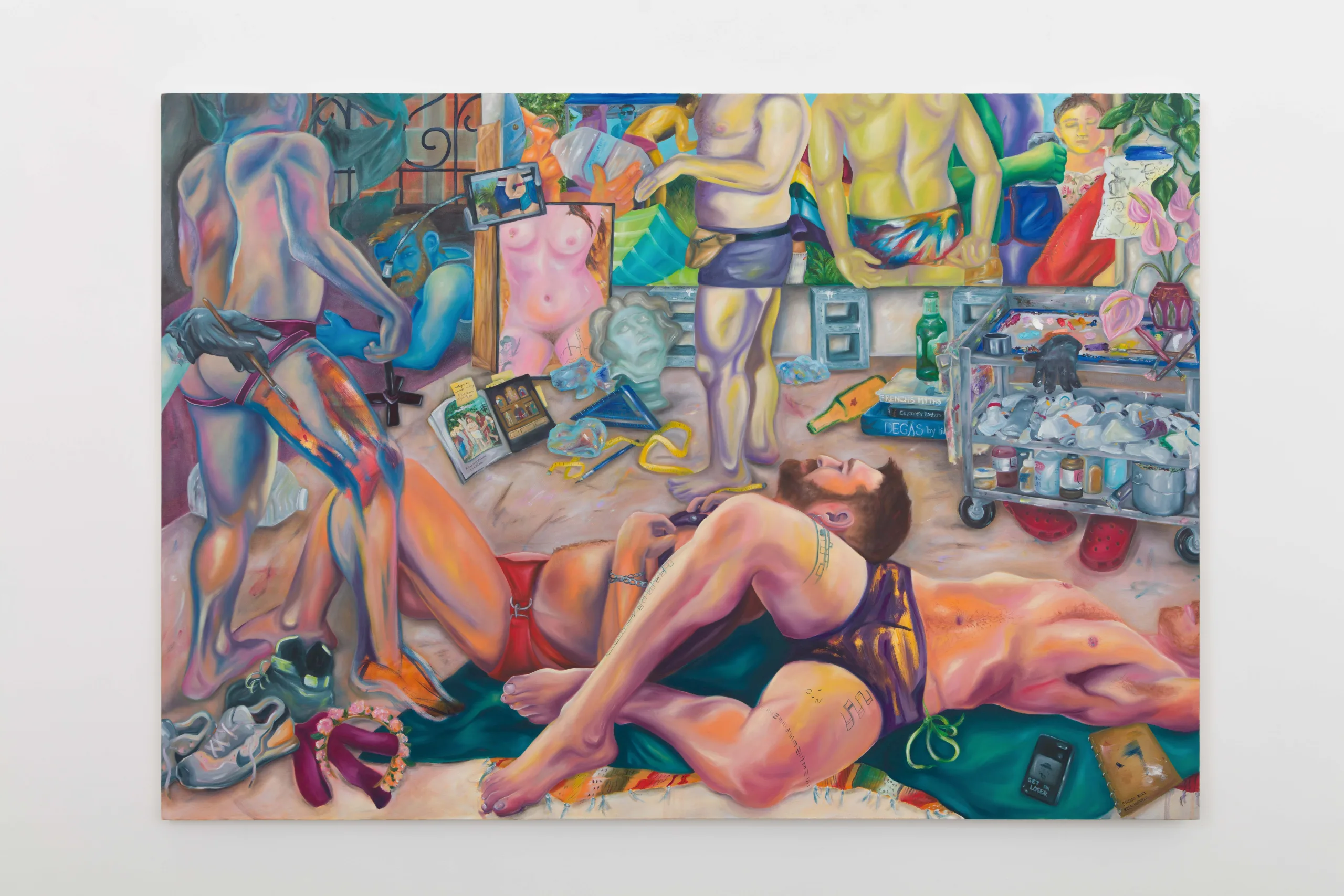 A painting depicts a room with a man and woman. Two figures lie on the floor, one being painted on, while another paints a large canvas. There are painting materials on the floor even sneakers and a crocs.