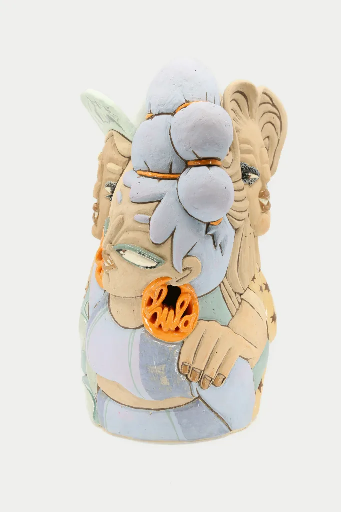 A carved and glazed ceramic vessel depicting a group of women. The three visible women are looking in different directions and are positioned with their profiles facing the viewer. The frontmost one has an orange earring that reads "Chula."