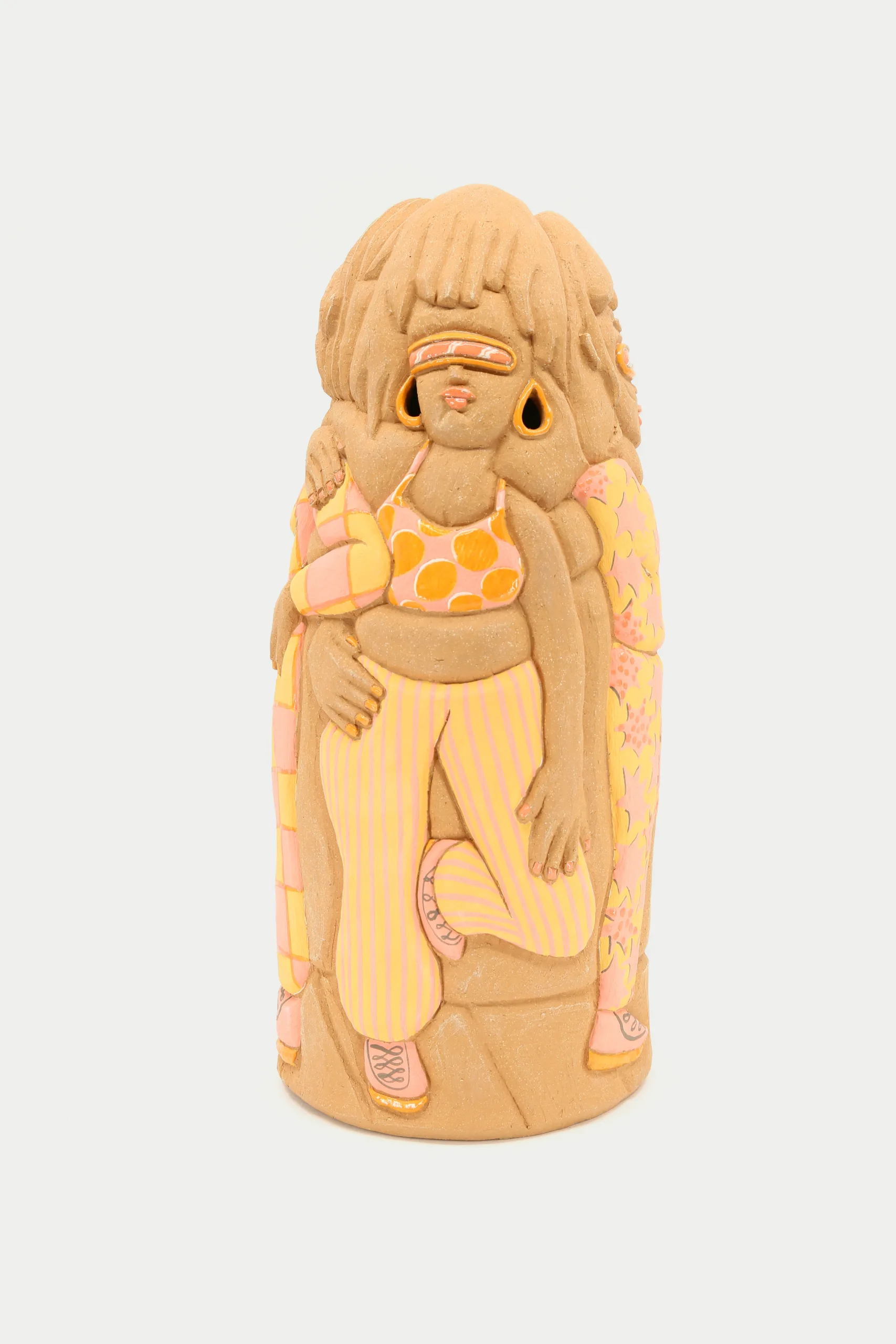 A carved and glazed ceramic vessel depicting a group of women wearing light orange outfits. The one in front looks up and holds her gaze confidently as the others stand by her side.