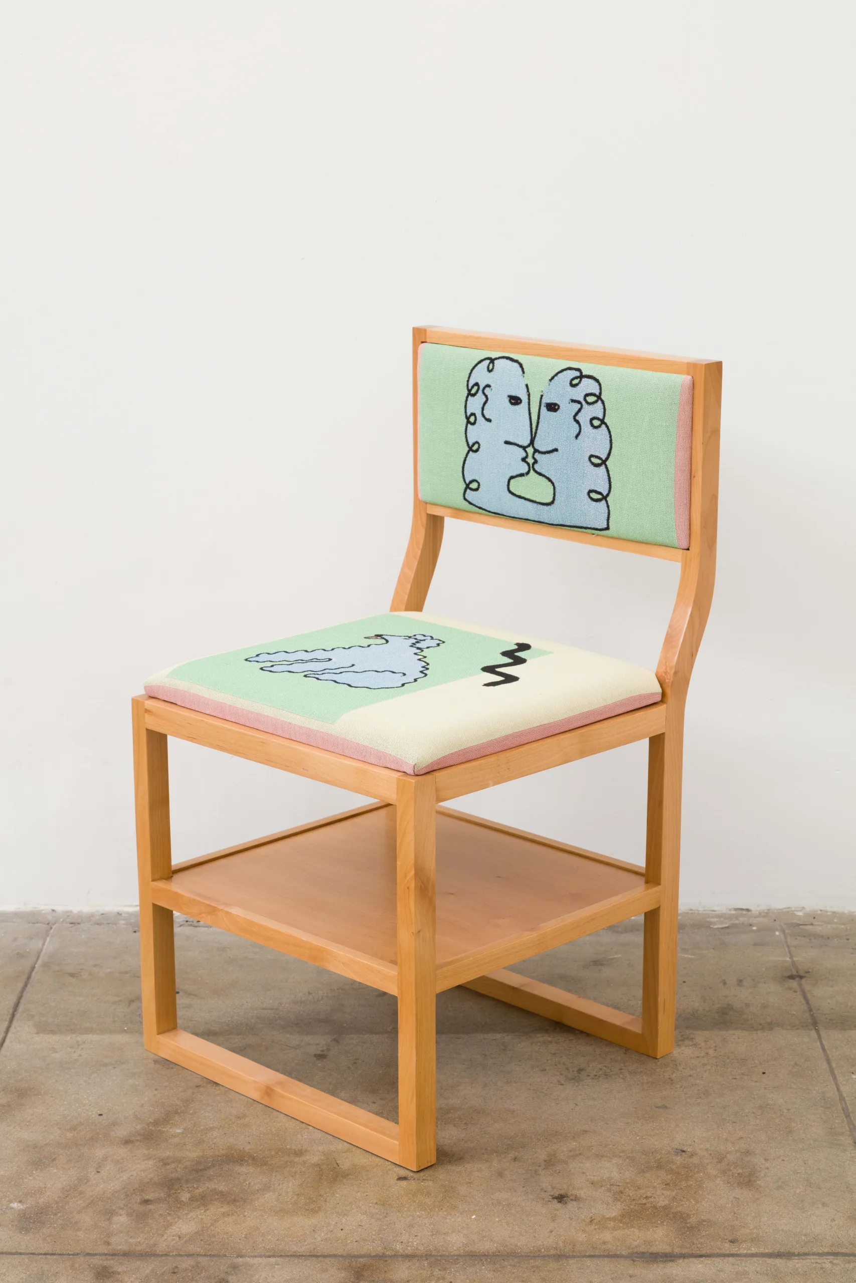 A wooden chair with a shelf under its seat. The seat and back rest cushions are woven and depict line drawings of a dog and two people kissing, respectively. In the background is a field of green, pink, and light beige blocks of color.