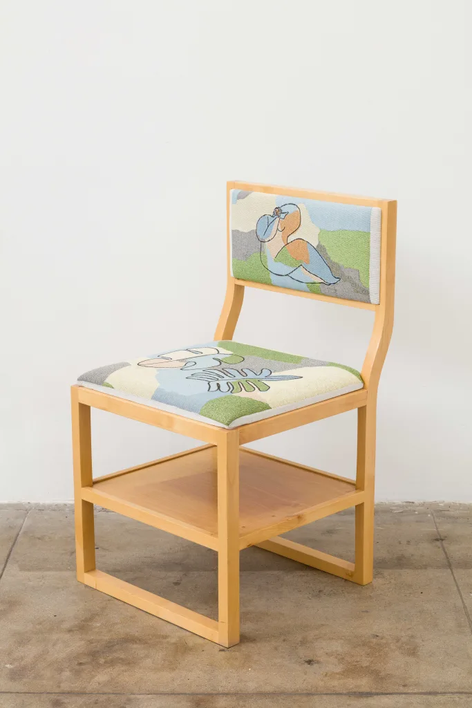 A wooden chair with a shelf under its seat. The seat and back rest cushions are woven and depict line drawings of leaves and a nude woman reclining, respectively. In the background is a field of blue, green, gray, and light beige blocks of color.