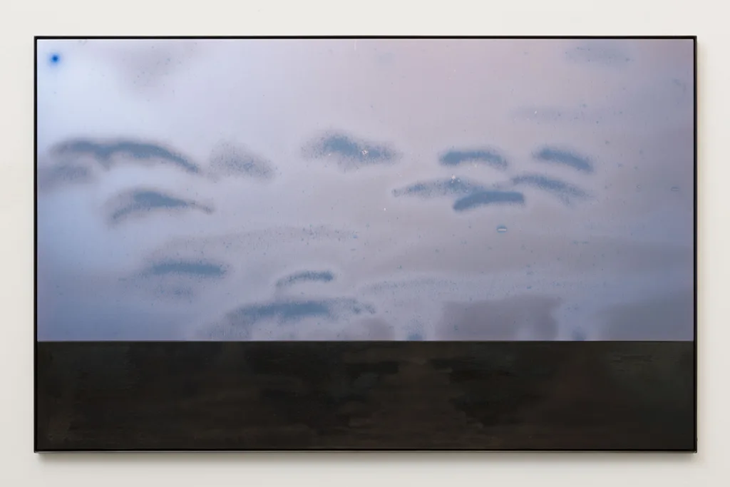 A blue/pink plate of anodized aluminum sanblasetd with cloud-like marks sits above a blued steel plate with similar sandblasting. In the top right corner there is a darker spot of blue that resembles a moon. The ambient light that reflects off this piece changes the brightness and tone of certain areas.